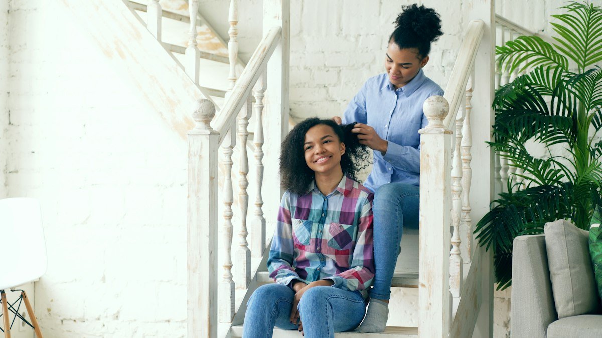 Mother braiding her daughter's hair on the stairs